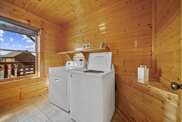 clothes washing area with light tile patterned floors, washing machine and clothes dryer, wooden walls, and wood ceiling