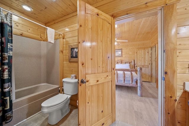 bathroom featuring hardwood / wood-style floors, shower / tub combo with curtain, wooden walls, and toilet