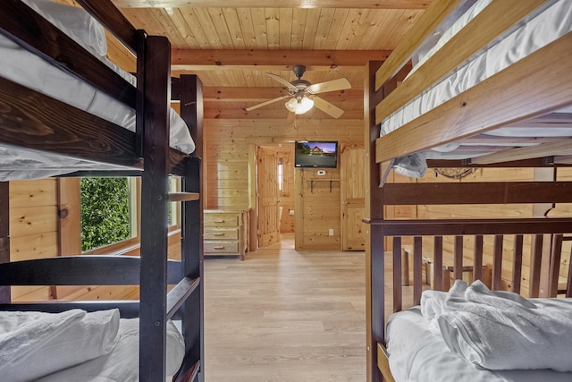 bedroom featuring wooden walls, ceiling fan, light hardwood / wood-style floors, wooden ceiling, and beam ceiling