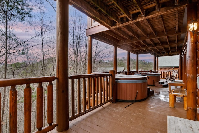 deck at dusk featuring a hot tub