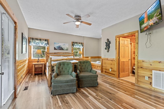 bedroom featuring hardwood / wood-style flooring, wooden walls, and multiple windows