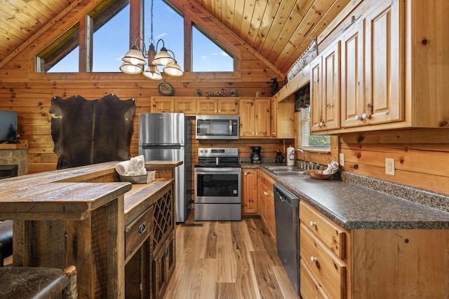 kitchen featuring sink, wooden walls, vaulted ceiling, stainless steel appliances, and a chandelier