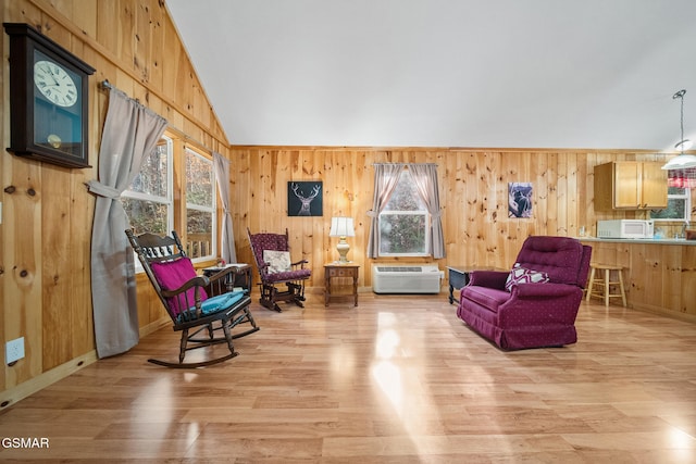 sitting room with a wall mounted air conditioner, light hardwood / wood-style floors, wood walls, and vaulted ceiling