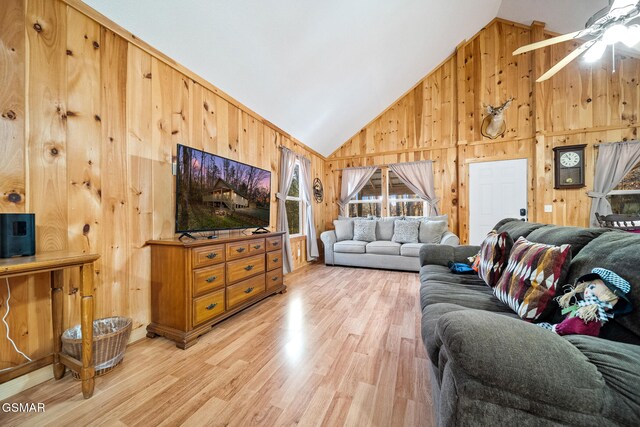 living room featuring high vaulted ceiling, ceiling fan, wood-type flooring, and wooden walls