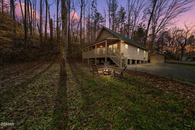 back house at dusk with a storage unit, an outdoor fire pit, and a wooden deck