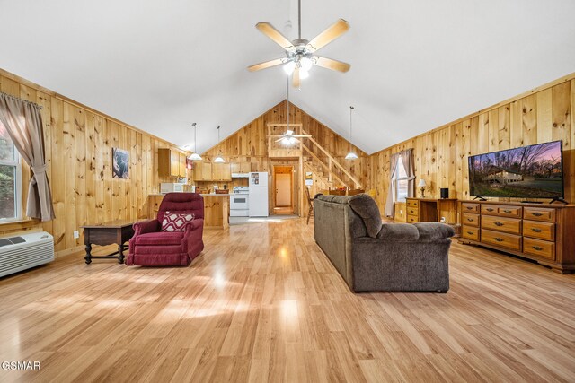 living room featuring ceiling fan, wood walls, lofted ceiling, and light wood-type flooring