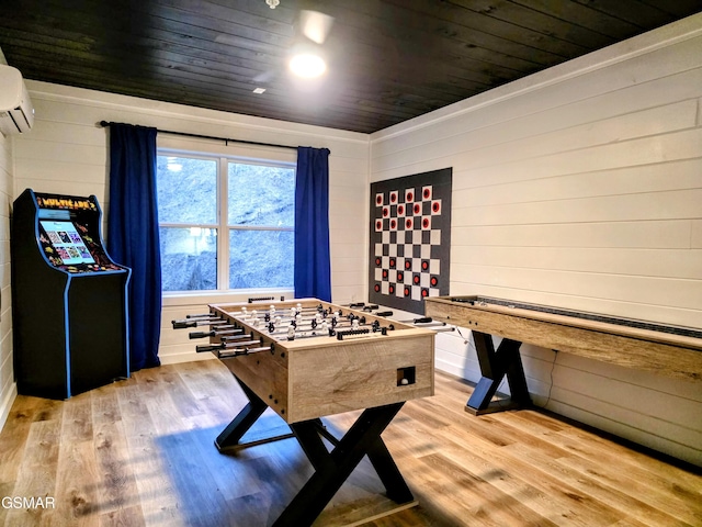 recreation room with light wood-style floors, wood ceiling, an AC wall unit, and wooden walls