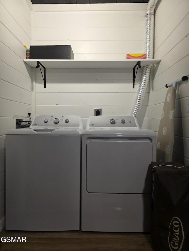 laundry room with laundry area, wooden walls, independent washer and dryer, and dark wood-style floors