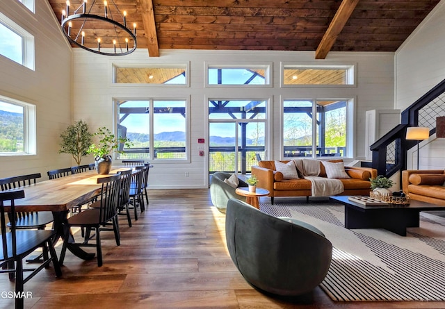 living area featuring a towering ceiling, a healthy amount of sunlight, hardwood / wood-style floors, and beamed ceiling
