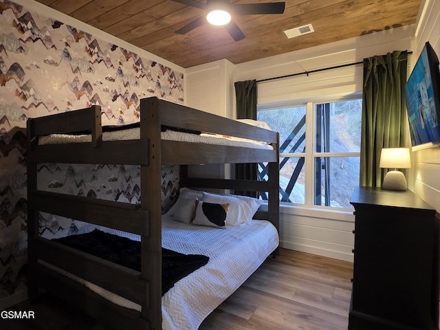 bedroom featuring a ceiling fan, visible vents, wood finished floors, wooden ceiling, and wallpapered walls