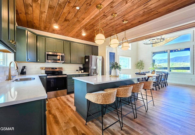 kitchen with appliances with stainless steel finishes, a wealth of natural light, wood ceiling, and a kitchen bar