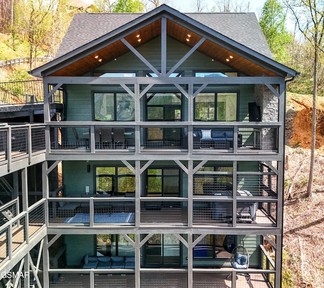 rear view of house with roof with shingles and a balcony