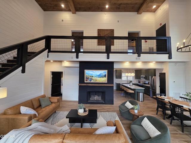 living room with light wood-type flooring, a fireplace, beam ceiling, and wooden ceiling