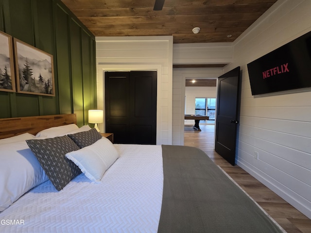 bedroom with wood finished floors, wooden walls, and wooden ceiling