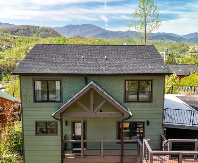 rear view of property with roof with shingles and a mountain view