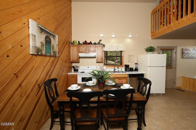 tiled dining space featuring wood walls and sink