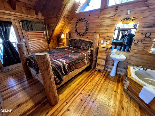 bedroom featuring lofted ceiling, light wood-style floors, and wood walls