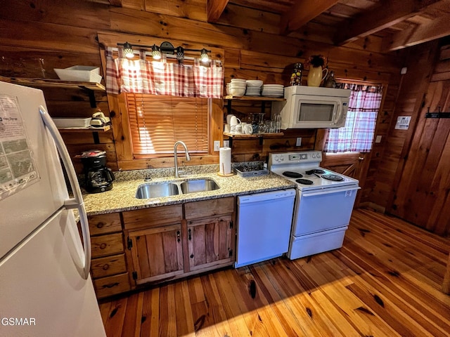 kitchen featuring dark wood finished floors, white appliances, wooden walls, and a sink