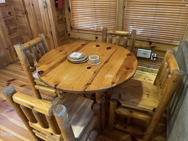 dining space with wooden walls and wood finished floors