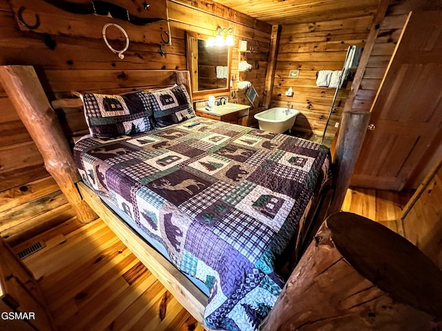 bedroom featuring visible vents, wood walls, wooden ceiling, and wood finished floors