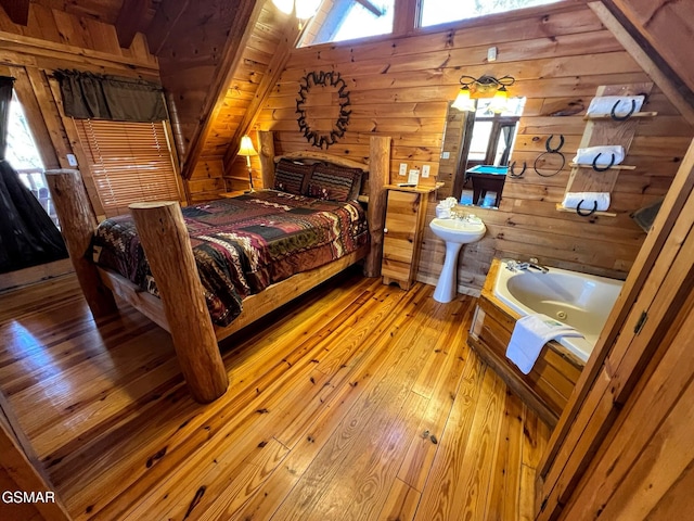 bedroom with light wood-style floors, wood walls, and a sink