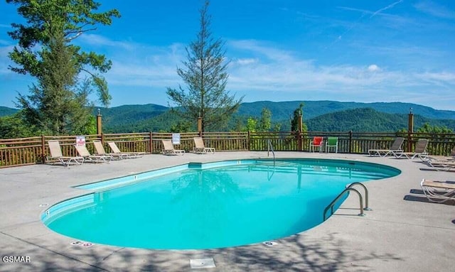 community pool featuring a patio, fence, and a mountain view