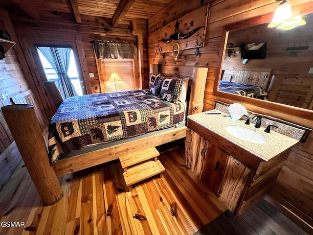 bedroom with beam ceiling, a sink, wood finished floors, wooden ceiling, and wood walls