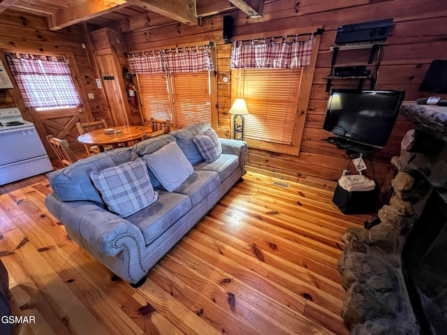 living area with beamed ceiling, wooden walls, and hardwood / wood-style floors