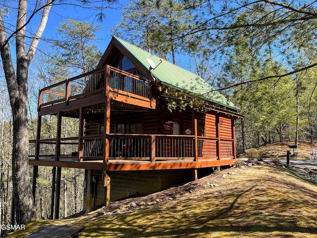 exterior space featuring metal roof, a wooden deck, and faux log siding