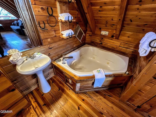 bathroom featuring wood-type flooring, a jetted tub, and wood walls