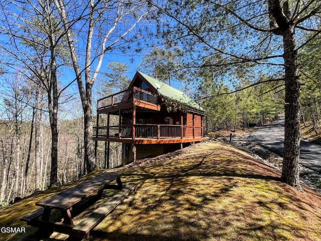 exterior space with metal roof, a view of trees, and a deck