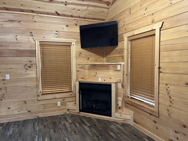 unfurnished living room featuring dark hardwood / wood-style flooring and wooden walls