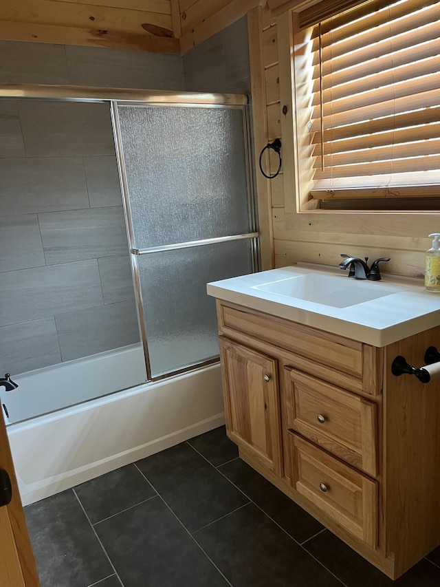 bathroom with tile patterned floors, vanity, wood walls, and shower / bath combination with glass door