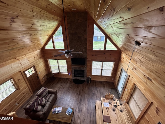 unfurnished living room with wood walls, high vaulted ceiling, ceiling fan, a fireplace, and wood ceiling