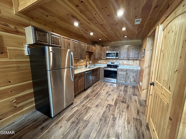 kitchen featuring wood walls, sink, appliances with stainless steel finishes, dark hardwood / wood-style flooring, and wood ceiling