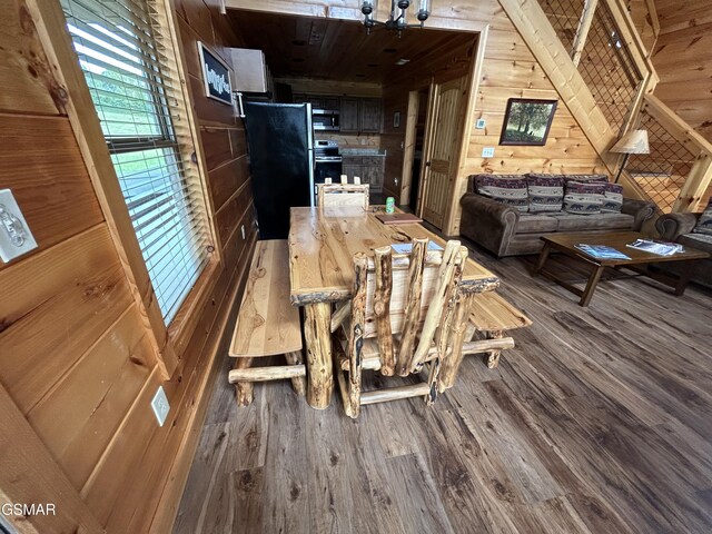 dining room with hardwood / wood-style floors, wood walls, and lofted ceiling