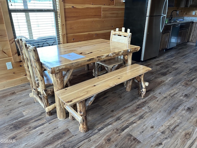 unfurnished dining area with hardwood / wood-style floors, sink, and wood walls