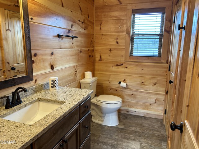 bathroom featuring vanity, wood walls, and toilet