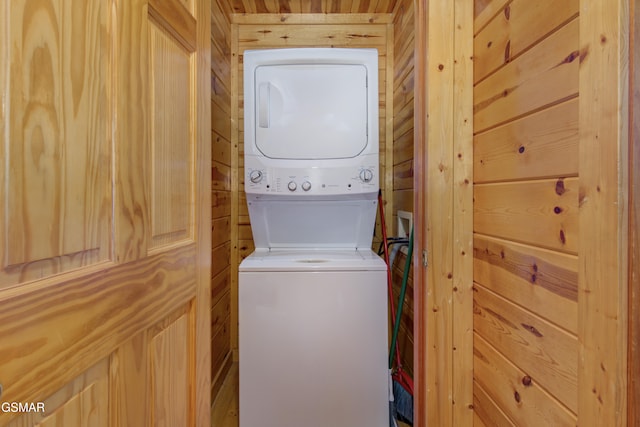 laundry room featuring wooden walls and stacked washer / drying machine