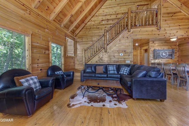 living room featuring beamed ceiling, light hardwood / wood-style flooring, and wooden walls