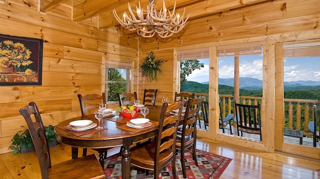 dining area featuring a mountain view, hardwood / wood-style floors, beamed ceiling, and a notable chandelier