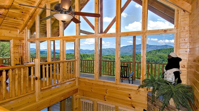 sunroom / solarium featuring a mountain view, ceiling fan, wooden ceiling, and vaulted ceiling