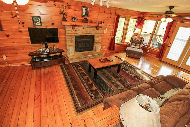 living room with hardwood / wood-style flooring, ceiling fan, a fireplace, and a textured ceiling