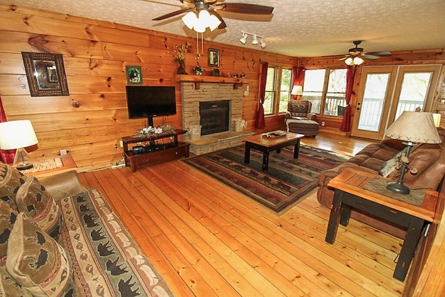 living room with wood walls, light hardwood / wood-style flooring, and a textured ceiling