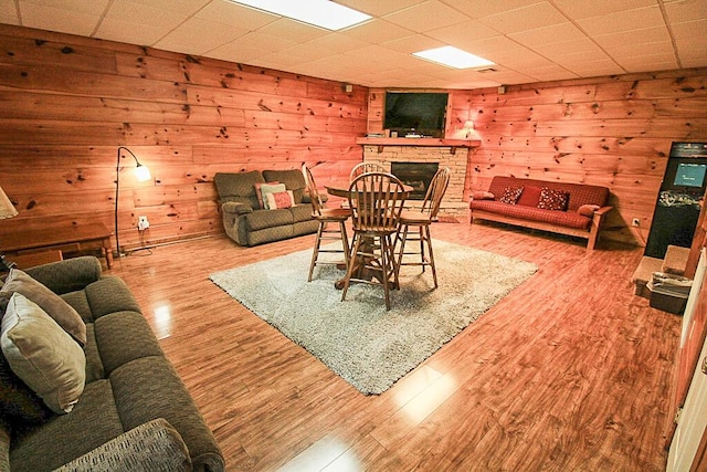 living room featuring light hardwood / wood-style floors, a fireplace, and wooden walls