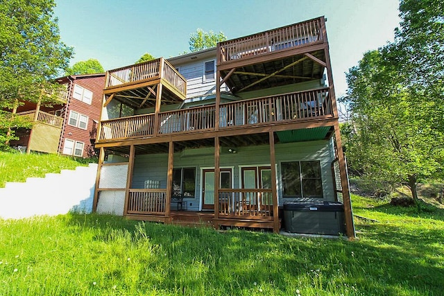 rear view of house featuring a hot tub and a lawn