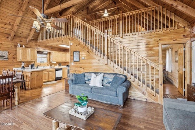 living room with beamed ceiling, ceiling fan, wood ceiling, and wood walls