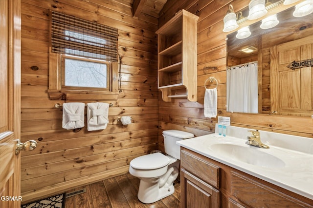 bathroom with toilet, wood-type flooring, vanity, and wood walls