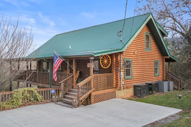1706 Springer Rd, Sevierville, TN 37862 - view of front facade featuring covered porch, cooling unit, log siding, metal roof, and a patio