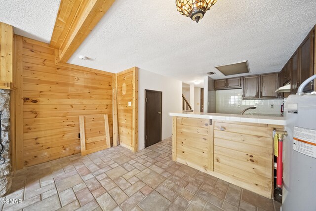 260 Roaring Fork Rd Unit 217, Gatlinburg, TN 37738 - kitchen with tile countertops, tasteful backsplash, water heater, stone finish floor, and wooden walls